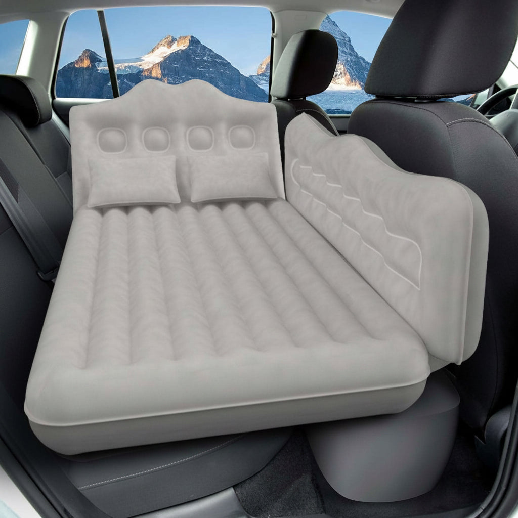 Inflatable car mattress with built-in pillow in a vehicle with mountainous landscape outside.